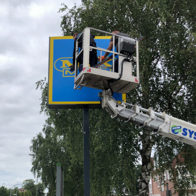 Mitarbeiter von Hansawerbung bringen mit Kran Lichtwerbung an