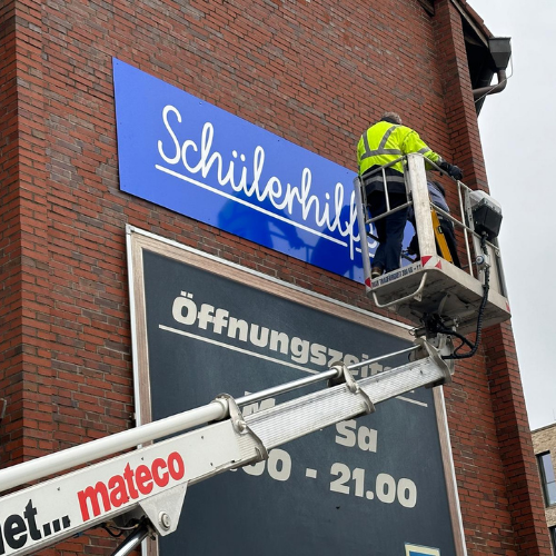 Anbringen von Folienbeschriftung auf Werbeschild
